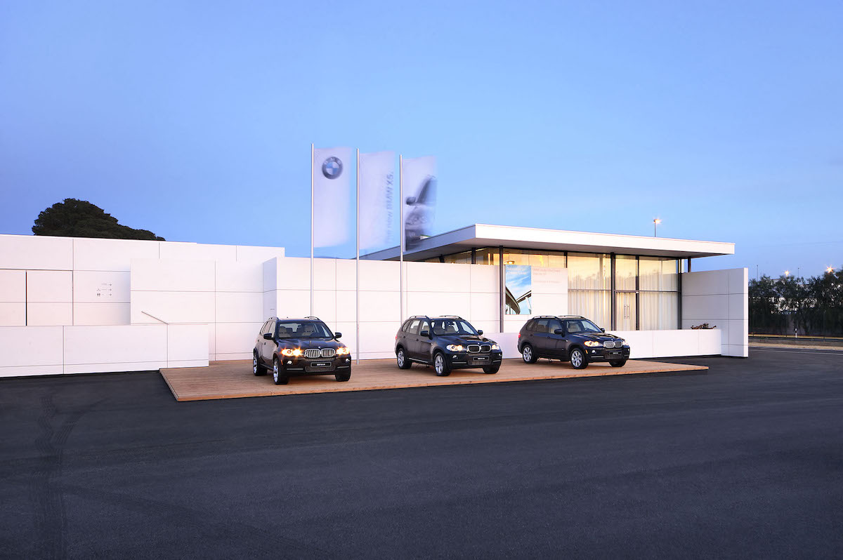 Drei schwarzen BMW Autos stehen vor einer weissen vorgehängten hinterluefteten Fassade.