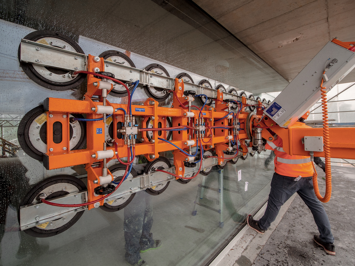 Die Übergrosse Panoramaverglasung wird mithilfe des orangen Glassaugers und ein Mitarbeiter ein