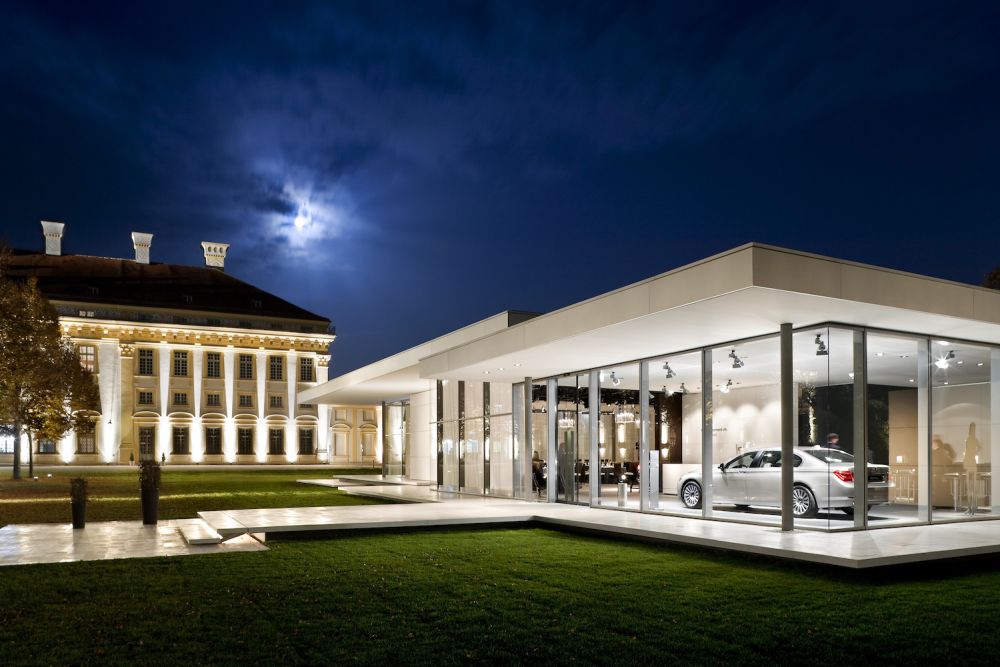 Beleuchteter BMW Kubus Pavillon mit Glasfassade abends