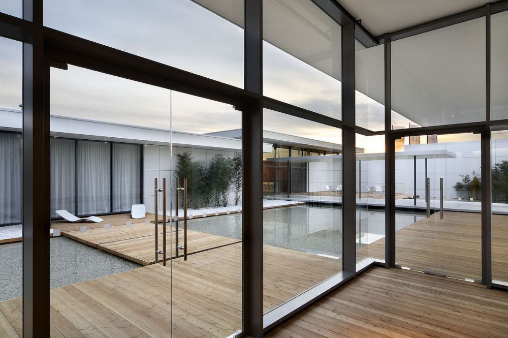 Structural Glazing Fassade des BMW Oracle Pavillons mit Glastüren und Festverglasung. Der Pavillon hat Pools und Holzboden.