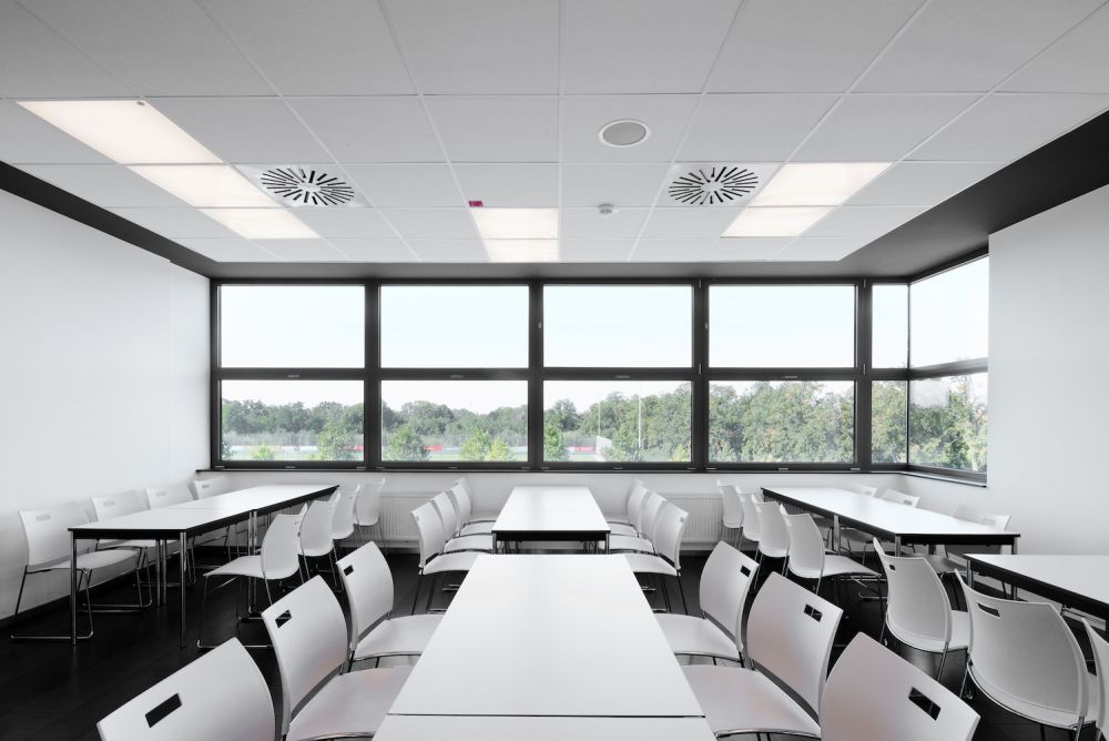 Sitzungsraum mit Tischreihen, Stühlen und Structural Glazing Fenstern