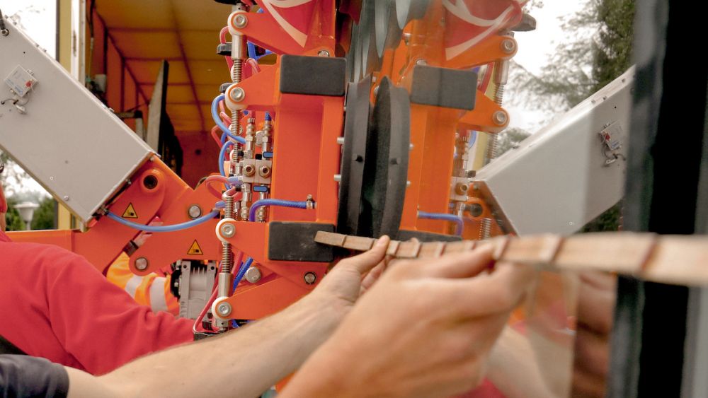 Hände von Mitarbeiter halten einen Holzmeter, um die Übergrosse Panoramaverglasung zu messen