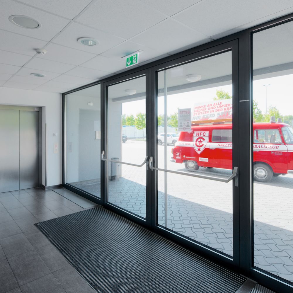 Innenaufnahmen von die Ausgangstüren im Windfang des Erdgas Sportpark in Halle. Draußen hinter der Tür steht das offizielle rote Fahrzeug des Fußballvereins. 