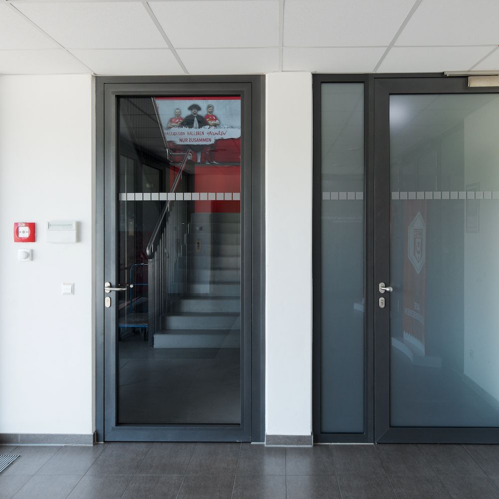 Zwei Brandschutztüren mit Glas stehen nebeneinander im Windfang vom Erdgas Sportpark in Halle.