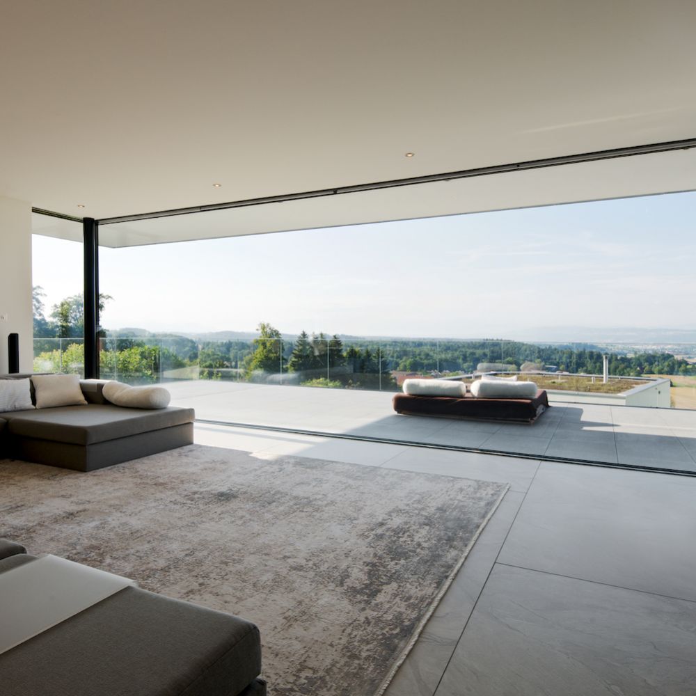 Luxus Wohzimmer mit übergrosse Panoramaverglasung, Terrasse und Blick auf die Berge