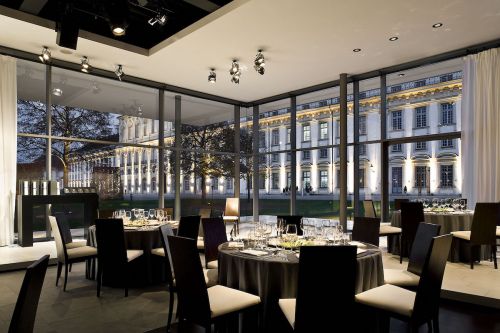 Speisesaal im Inneren des BMW Kubus-Pavillons mit Glasfassade abends