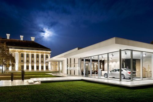 BMW Kubus Pavillon mit Glasfassade und grauem Auto im Innenbereich