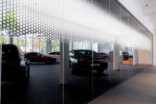 Perspektivische Aufnahme von dunkler Innenglaswand mit Widerspieglung von Mercedes Autos