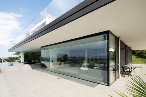 Übergrosse Panoramaverglasung von moderner Villa mit Pool und Terrasse